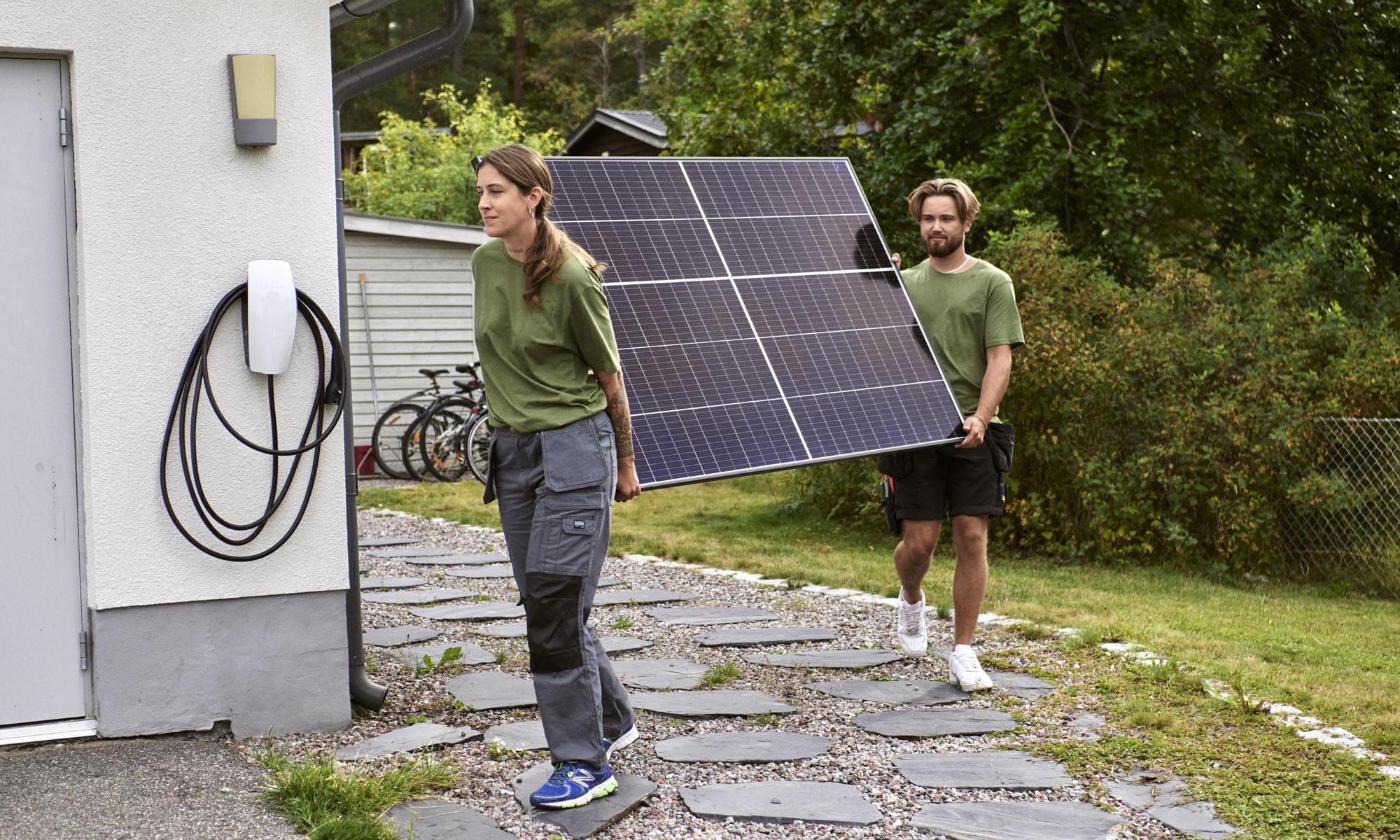 Two workers carrying solar panel together