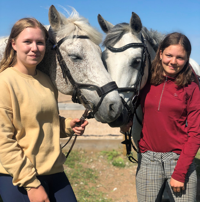 Två tjejer står vid en häst.